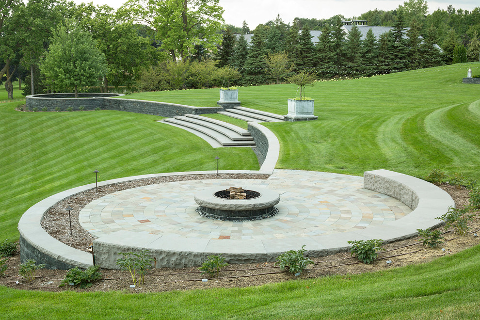Photo of a transitional backyard garden with a fire feature and natural stone pavers.