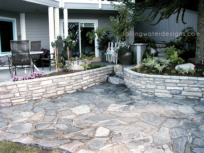 This is an example of a huge contemporary partial sun backyard stone retaining wall landscape in Seattle for summer.