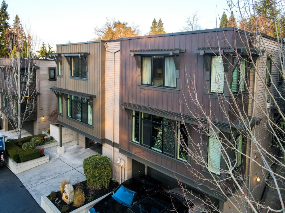 Mid-sized modern three-storey stucco brown townhouse exterior in Seattle with a flat roof, a mixed roof, a brown roof and board and batten siding.