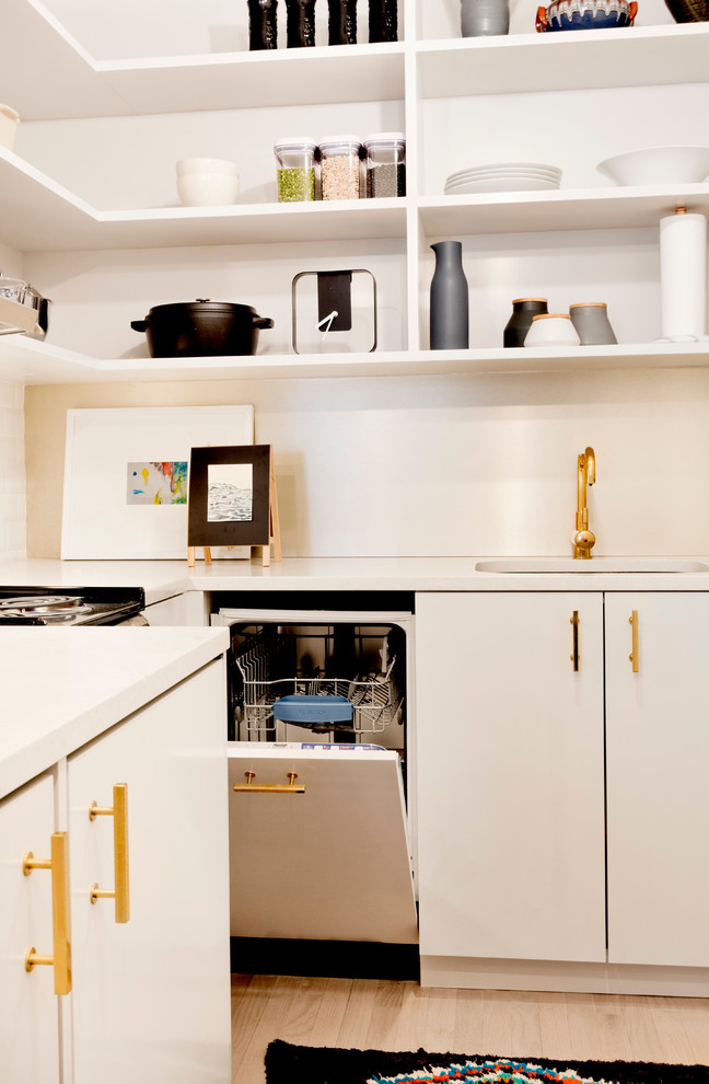 Photo of a small modern l-shaped open plan kitchen in New York with an undermount sink, open cabinets, white cabinets, quartz benchtops, white splashback, subway tile splashback, panelled appliances, light hardwood floors and no island.
