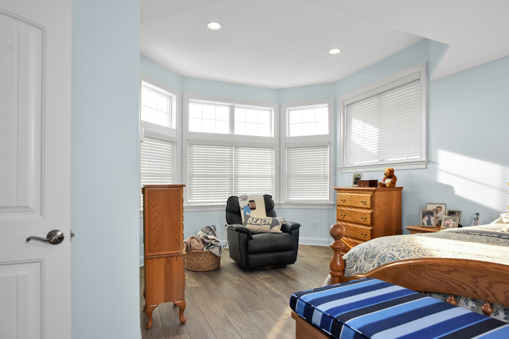 Modelo de dormitorio principal ecléctico de tamaño medio con paredes azules, suelo vinílico, suelo marrón y bandeja