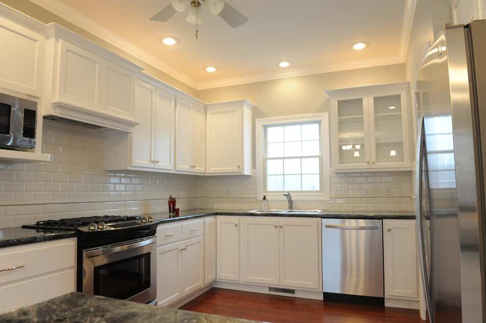 Example of a transitional u-shaped eat-in kitchen design in Chicago with a drop-in sink, flat-panel cabinets, white cabinets, laminate countertops, white backsplash and subway tile backsplash