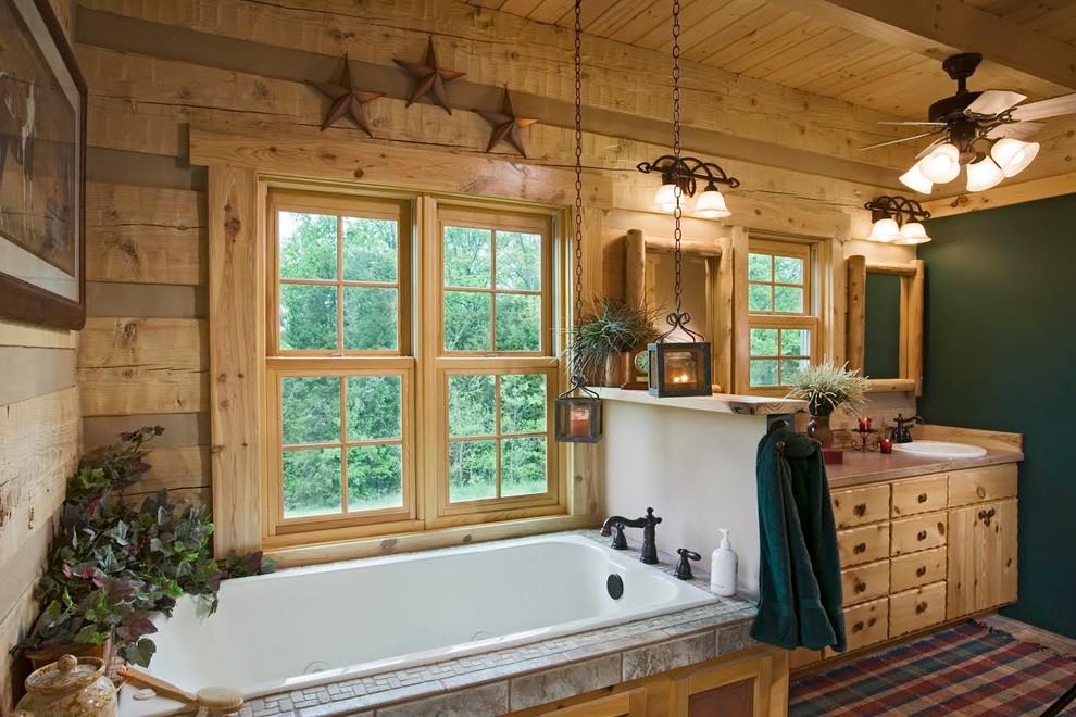 Example of a mid-sized mountain style master ceramic tile and beige floor drop-in bathtub design with furniture-like cabinets, light wood cabinets, green walls, a drop-in sink and granite countertops