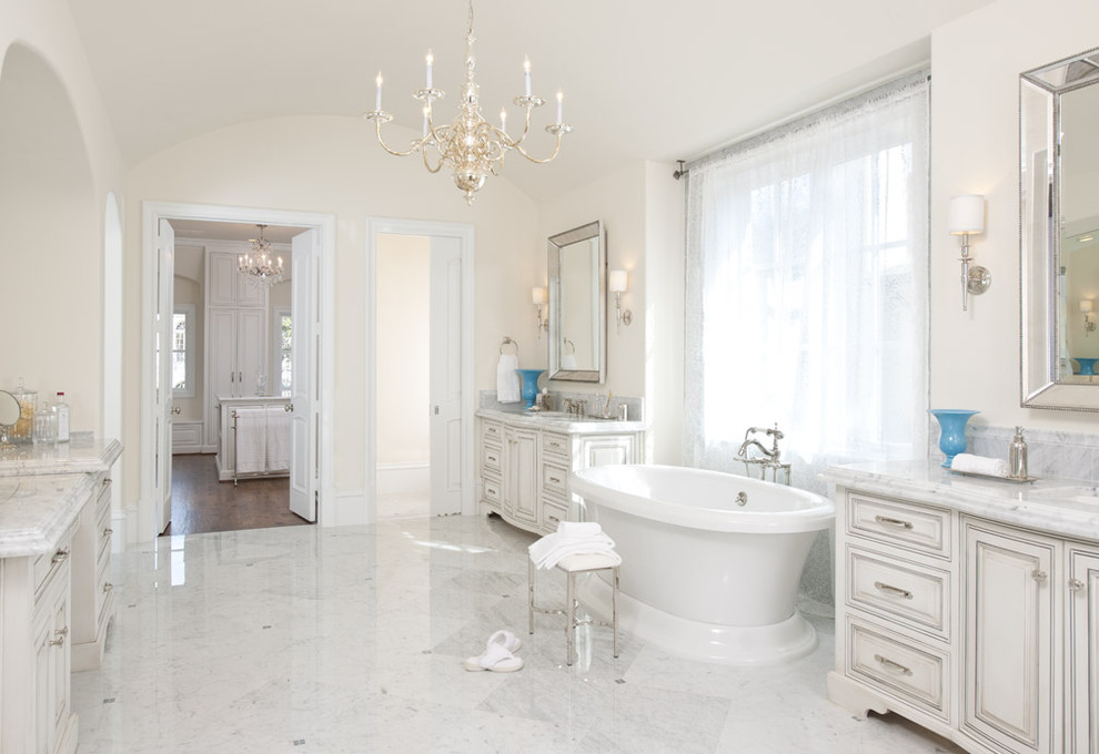 Design ideas for a large transitional master bathroom in Dallas with raised-panel cabinets, white cabinets, a freestanding tub, white tile, marble, beige walls, marble floors, an undermount sink, marble benchtops and white floor.