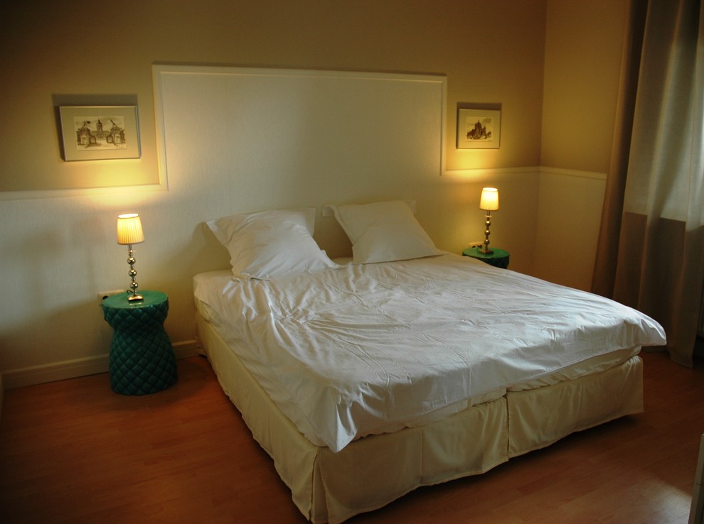 Modernes Schlafzimmer mit beiger Wandfarbe und braunem Holzboden in Sonstige