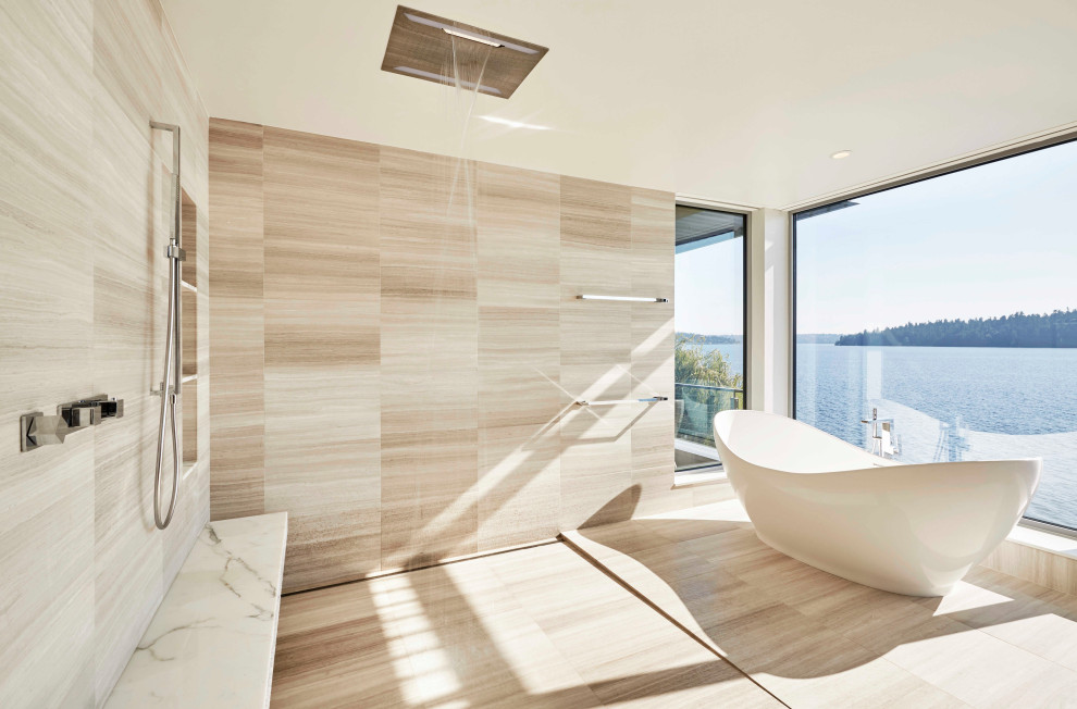 This is an example of a large contemporary master bathroom in Seattle with flat-panel cabinets, medium wood cabinets, a freestanding tub, a one-piece toilet, beige tile, porcelain tile, beige walls, porcelain floors, an undermount sink, limestone benchtops, beige floor, beige benchtops, an open shower and an open shower.