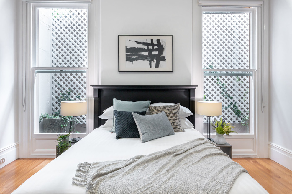 Inspiration for a scandinavian bedroom in Sydney with white walls, medium hardwood floors and brown floor.