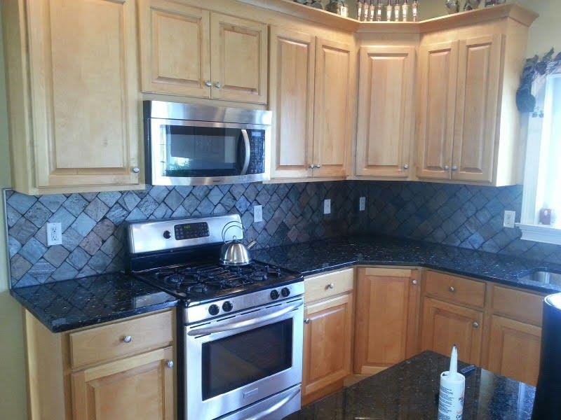 Example of a mid-sized l-shaped open concept kitchen design with raised-panel cabinets, light wood cabinets, granite countertops, multicolored backsplash, stone tile backsplash, stainless steel appliances and an island