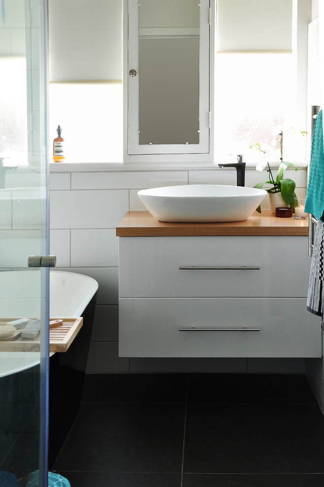 Small contemporary master bathroom in Melbourne with white cabinets, a freestanding tub, a corner shower, black and white tile, white walls, ceramic floors, a vessel sink and wood benchtops.
