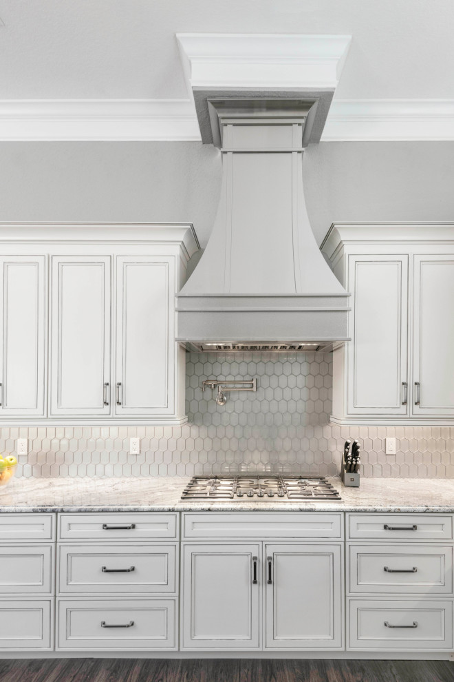 Kitchen - large transitional u-shaped laminate floor and multicolored floor kitchen idea in Orlando with an undermount sink, recessed-panel cabinets, white cabinets, granite countertops, metallic backsplash, glass tile backsplash, paneled appliances, an island and gray countertops
