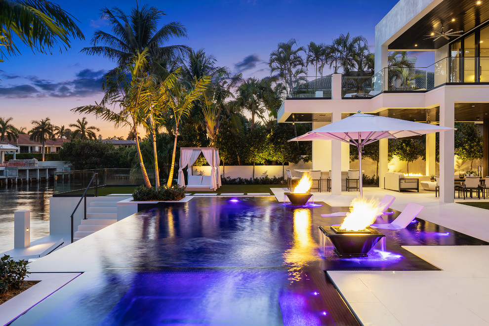 Photo of a large modern backyard rectangular infinity pool in Miami with a water feature and tile.