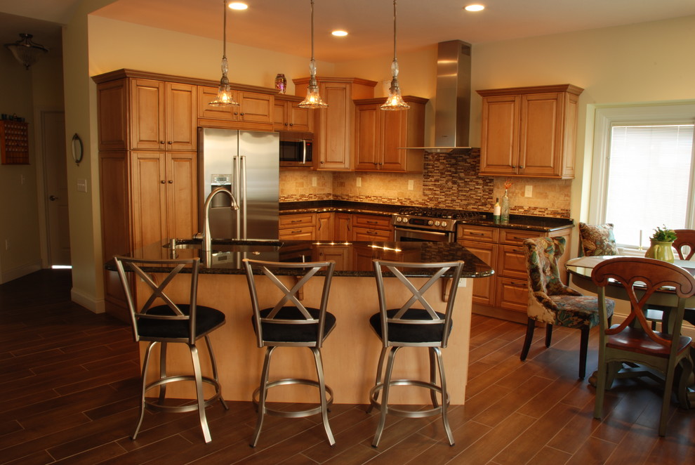 Inspiration for a mid-sized transitional l-shaped ceramic tile eat-in kitchen remodel with a farmhouse sink, raised-panel cabinets, medium tone wood cabinets, granite countertops, beige backsplash, ceramic backsplash, stainless steel appliances and an island