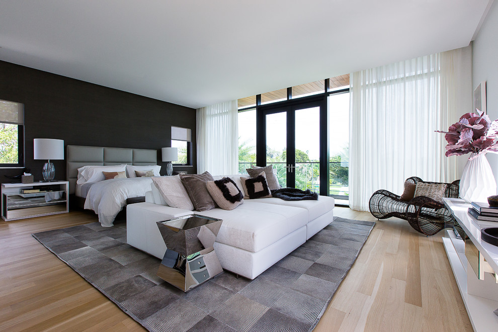 Large contemporary master bedroom in Miami with white walls and light hardwood floors.