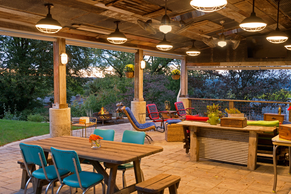 This is an example of a large country backyard patio in Other with concrete pavers and a roof extension.