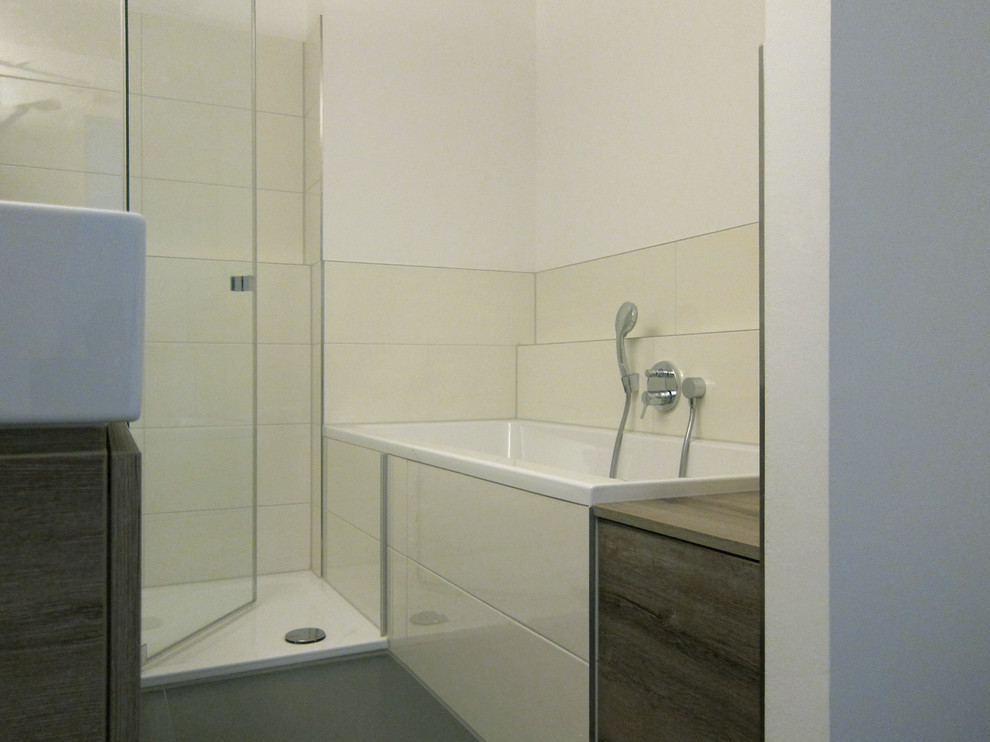 Idée de décoration pour une salle de bain design en bois brun de taille moyenne avec un placard à porte plane, une baignoire en alcôve, une douche à l'italienne, WC suspendus, un carrelage beige, des carreaux de céramique, un mur blanc, un sol en carrelage de porcelaine, une grande vasque, un sol gris et une cabine de douche à porte battante.