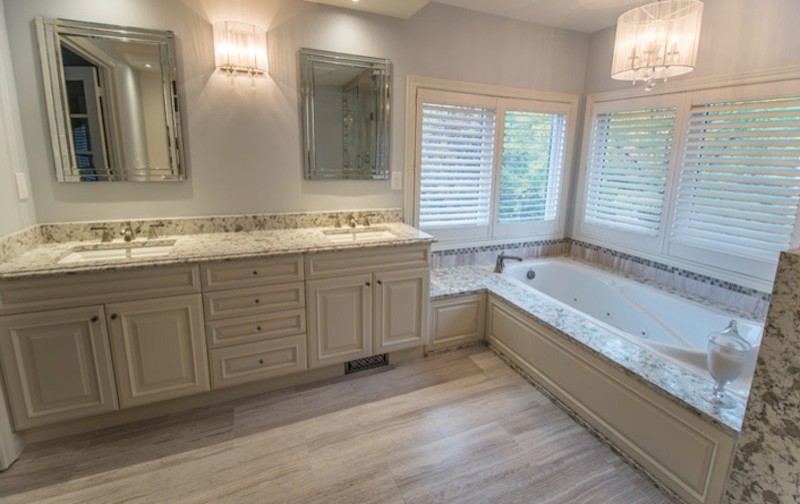 Design ideas for a mid-sized traditional master bathroom in New York with raised-panel cabinets, light wood cabinets, an undermount tub, beige tile, grey walls, porcelain floors, an undermount sink, granite benchtops, beige floor and multi-coloured benchtops.