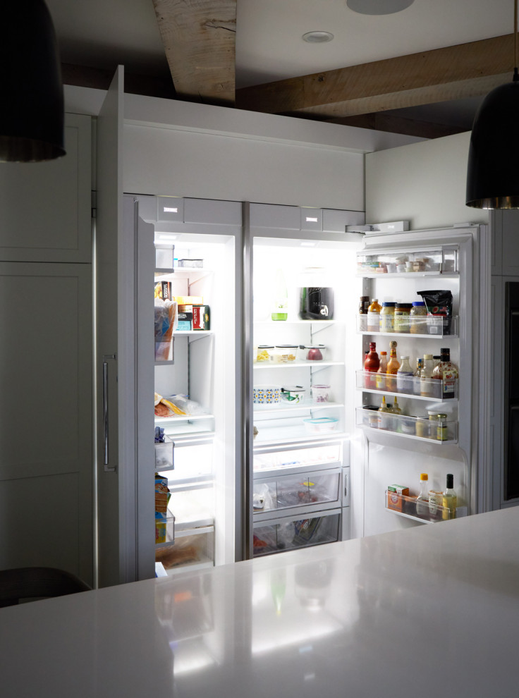 Example of a large transitional u-shaped medium tone wood floor, brown floor and exposed beam eat-in kitchen design in Chicago with an undermount sink, recessed-panel cabinets, white cabinets, quartz countertops, white backsplash, ceramic backsplash, paneled appliances, an island and white countertops