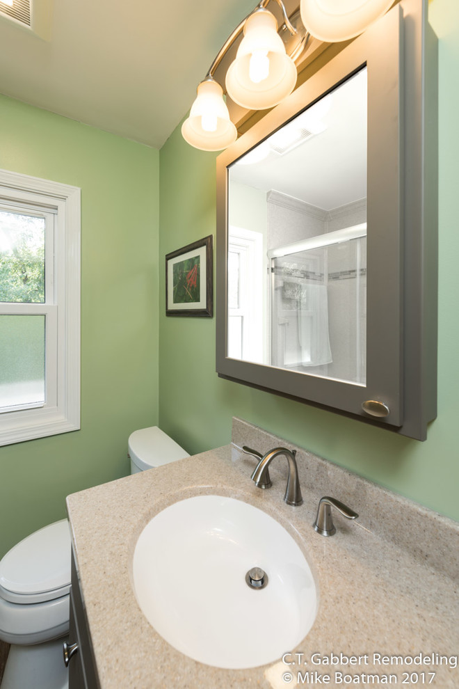 Photo of a small transitional 3/4 bathroom in Chicago with recessed-panel cabinets, grey cabinets, an alcove shower, multi-coloured walls, laminate floors, an integrated sink, onyx benchtops, brown floor and a sliding shower screen.