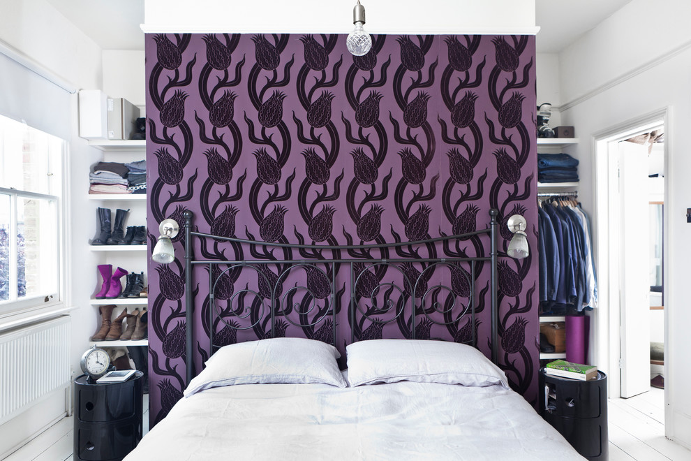 This is an example of an eclectic bedroom in London with purple walls and painted wood floors.