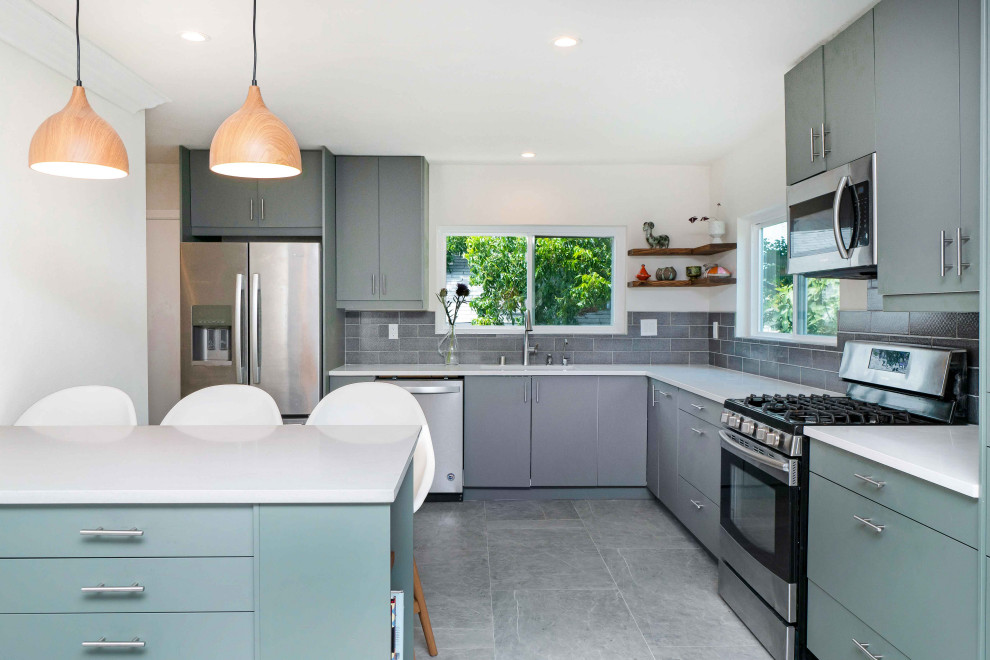 Inspiration for a contemporary l-shaped kitchen in Los Angeles with an undermount sink, flat-panel cabinets, grey cabinets, grey splashback, subway tile splashback, stainless steel appliances, a peninsula, grey floor and white benchtop.