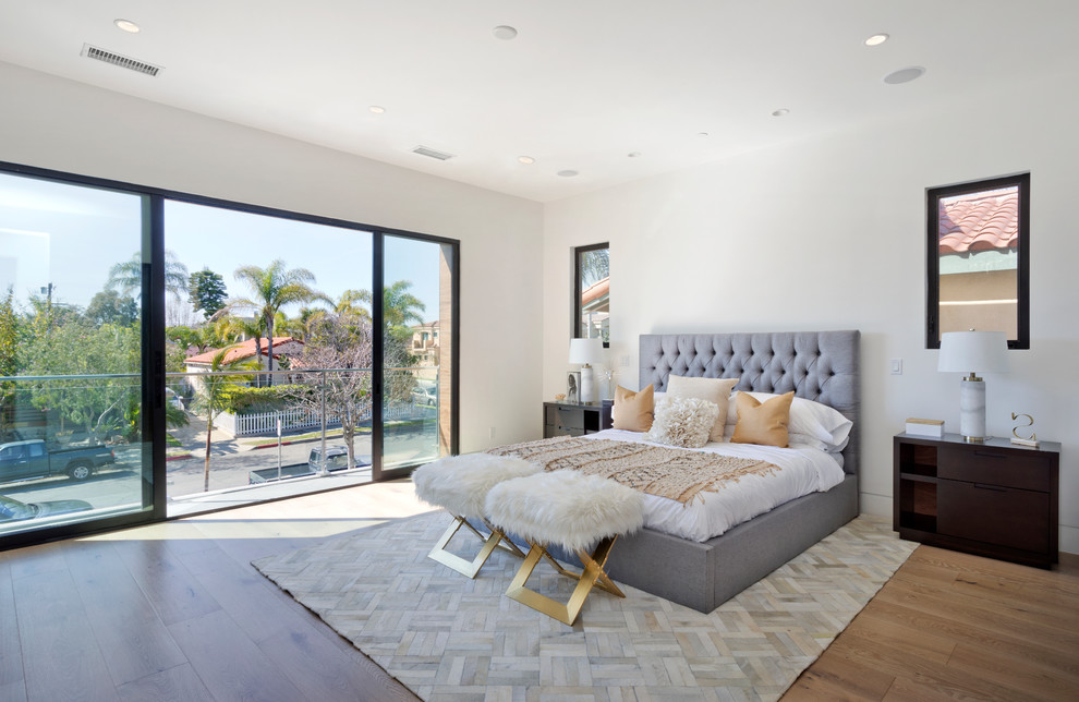This is an example of a mid-sized contemporary master bedroom in Orange County with white walls, light hardwood floors, no fireplace, beige floor and a metal fireplace surround.
