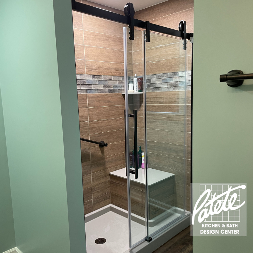 This is an example of a modern bathroom with an alcove shower, brown tile, wood-look tile, green walls, dark hardwood floors, brown floor and a sliding shower screen.