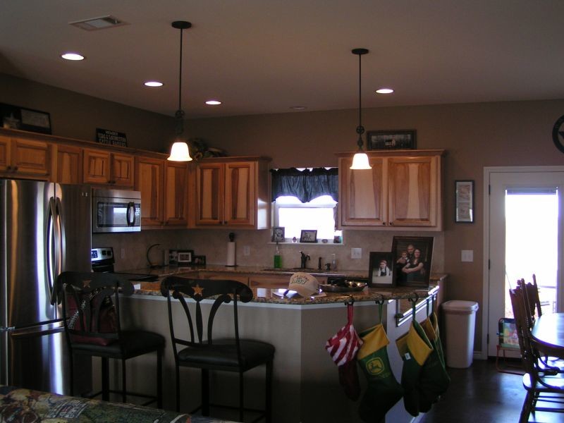 Example of a mid-sized u-shaped dark wood floor kitchen design with a drop-in sink, medium tone wood cabinets, granite countertops, beige backsplash, ceramic backsplash, stainless steel appliances and a peninsula