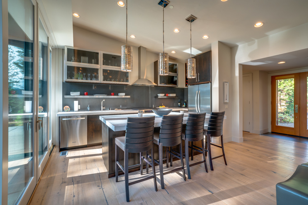 Photo of a contemporary l-shaped kitchen in Seattle with flat-panel cabinets, dark wood cabinets, grey splashback, stone slab splashback, medium hardwood floors, with island, brown floor and grey benchtop.