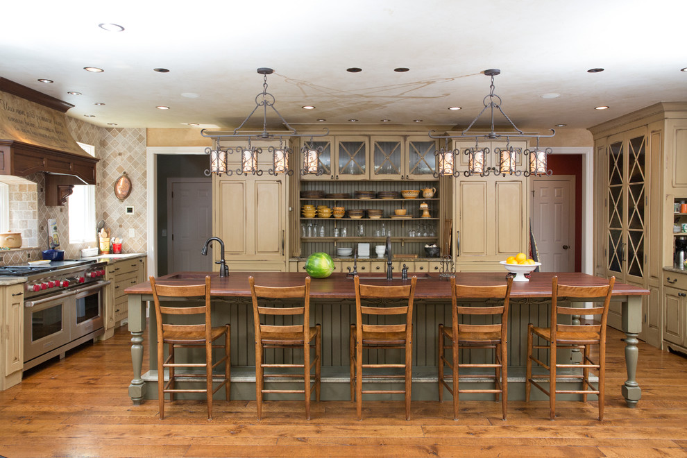This is an example of a large traditional l-shaped eat-in kitchen in Chicago with an undermount sink, wood benchtops, stone tile splashback, stainless steel appliances, medium hardwood floors, with island, beige cabinets and beige splashback.