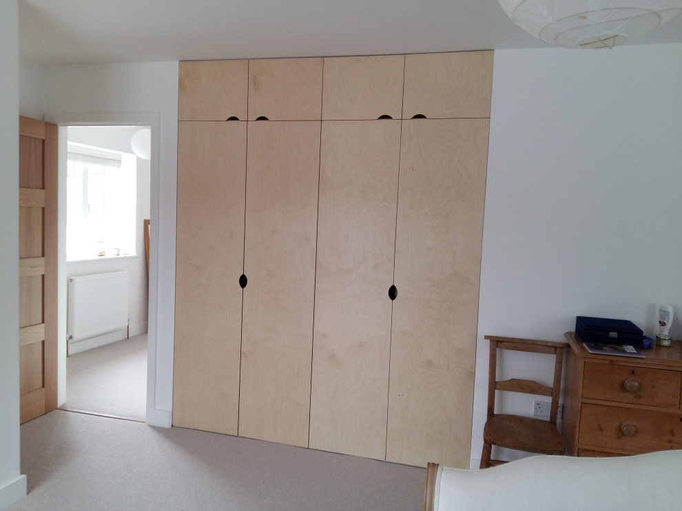 Diseño de armario y vestidor escandinavo extra grande con a medida, armarios con paneles lisos, puertas de armario de madera clara, moqueta y suelo gris