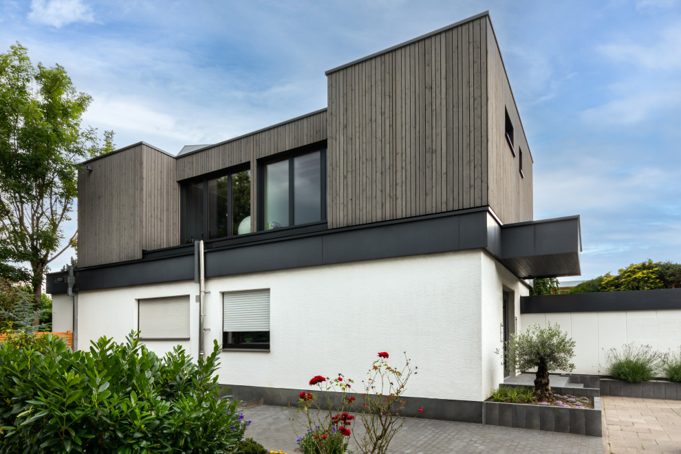 Immagine della facciata di una casa moderna di medie dimensioni con rivestimento in legno, tetto piano e pannelli sovrapposti