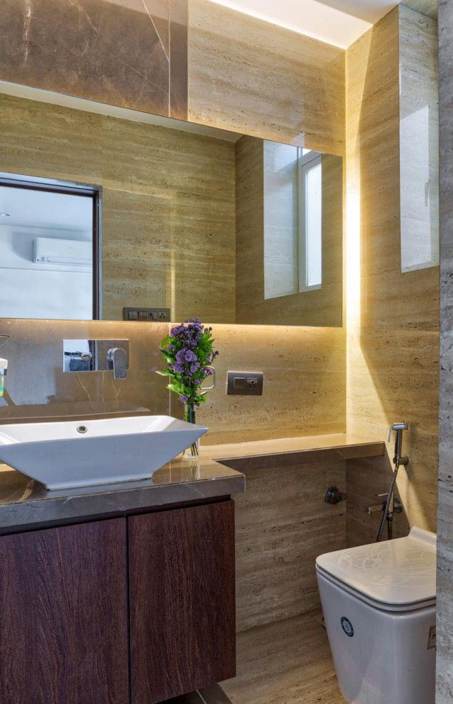 Photo of a contemporary powder room in Mumbai with flat-panel cabinets, medium wood cabinets, a wall-mount toilet, beige tile, brown tile, a vessel sink, beige floor and brown benchtops.