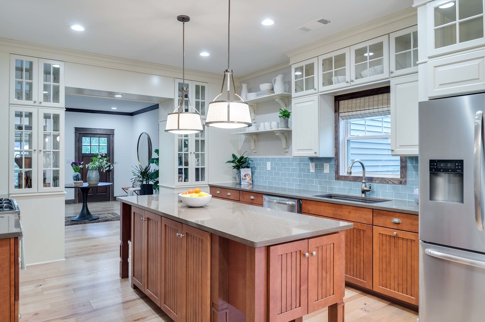 Inspiration for an arts and crafts u-shaped kitchen in Atlanta with an undermount sink, recessed-panel cabinets, medium wood cabinets, blue splashback, subway tile splashback, stainless steel appliances, light hardwood floors and with island.