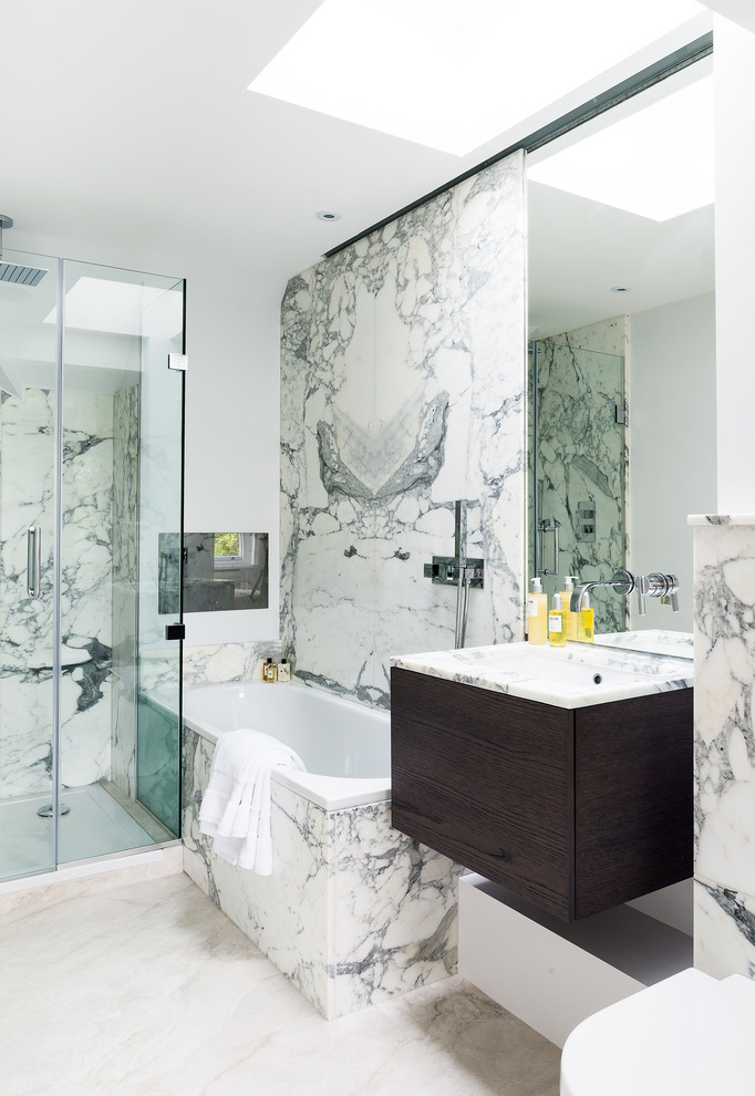 Inspiration for a mid-sized contemporary master bathroom in London with flat-panel cabinets, dark wood cabinets, gray tile, white tile, marble, white walls, marble benchtops, beige floor, a hinged shower door, white benchtops, a drop-in tub and an undermount sink.