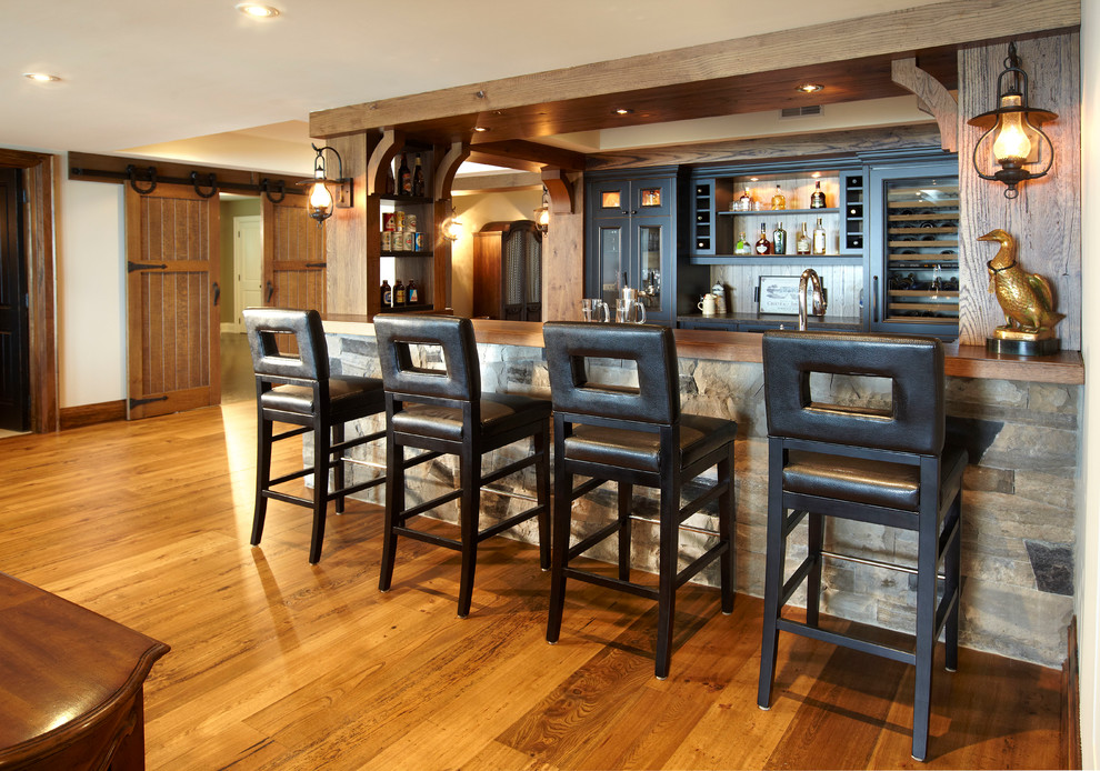 Photo of a mid-sized country galley seated home bar in Toronto with medium hardwood floors, wood benchtops, glass-front cabinets, distressed cabinets, brown floor and brown benchtop.