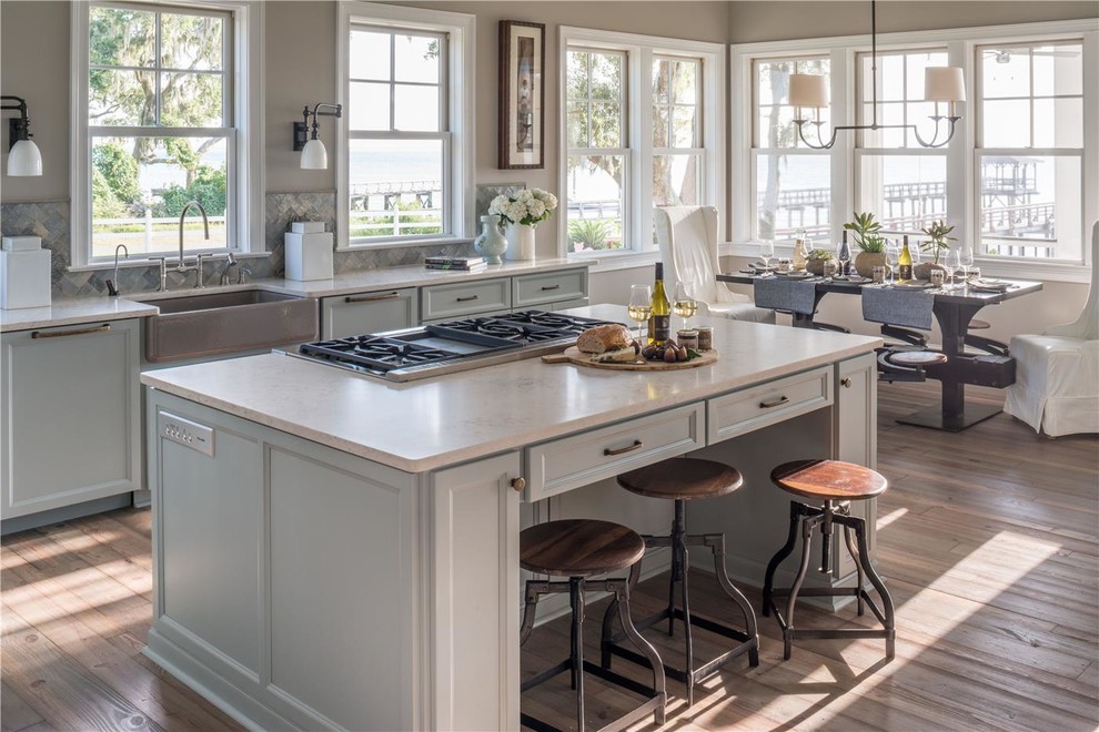 Inspiration for a large beach style l-shaped eat-in kitchen in Atlanta with a drop-in sink, raised-panel cabinets, light wood cabinets, granite benchtops, metallic splashback, metal splashback, stainless steel appliances, light hardwood floors and with island.