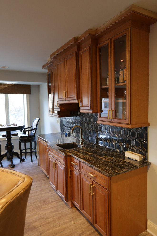 Mid-sized traditional single-wall wet bar in Baltimore with an undermount sink, raised-panel cabinets, medium wood cabinets, granite benchtops, black splashback, marble splashback, plywood floors, beige floor and black benchtop.