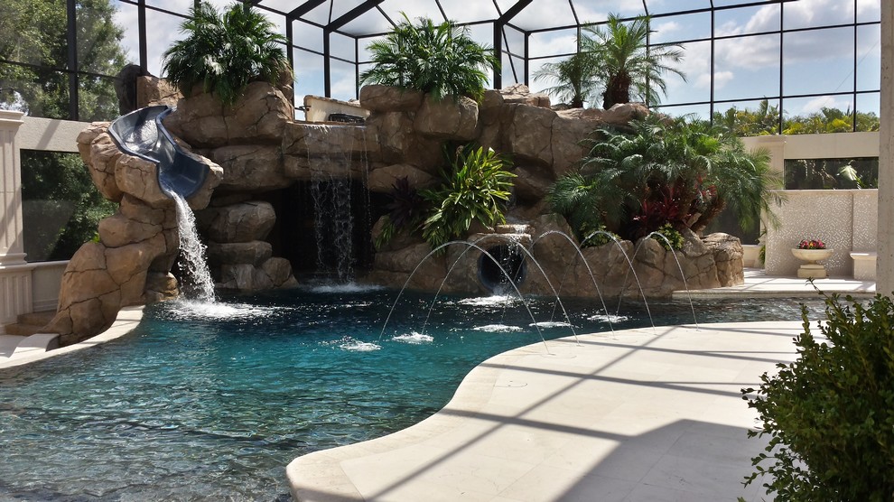 This is an example of a large contemporary backyard custom-shaped lap pool in Tampa with a water slide.