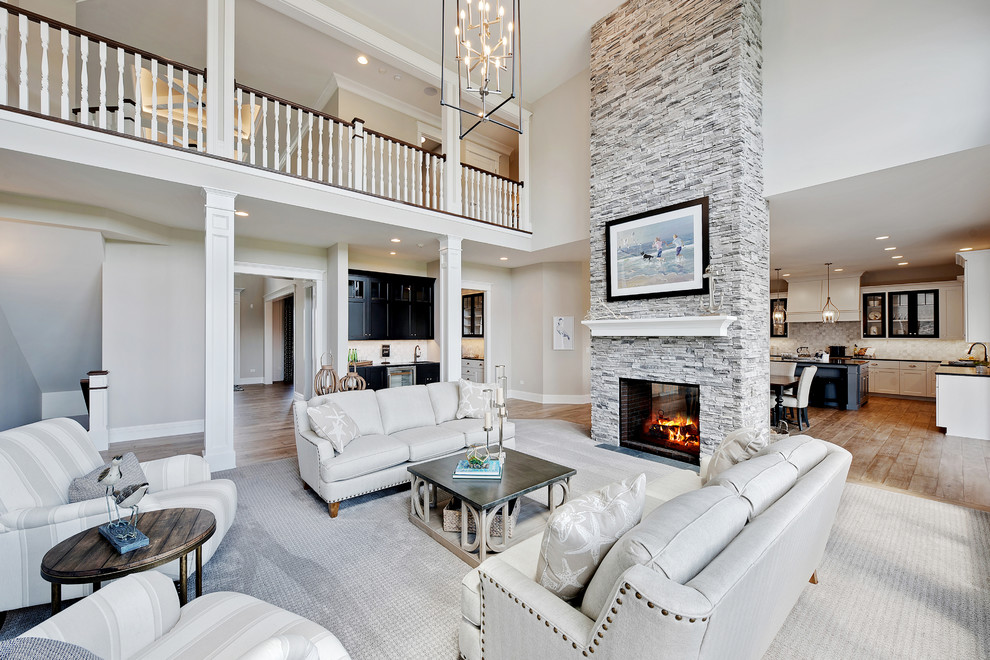 This is an example of a beach style formal open concept living room in Chicago with grey walls, medium hardwood floors, a two-sided fireplace, a stone fireplace surround, no tv and brown floor.