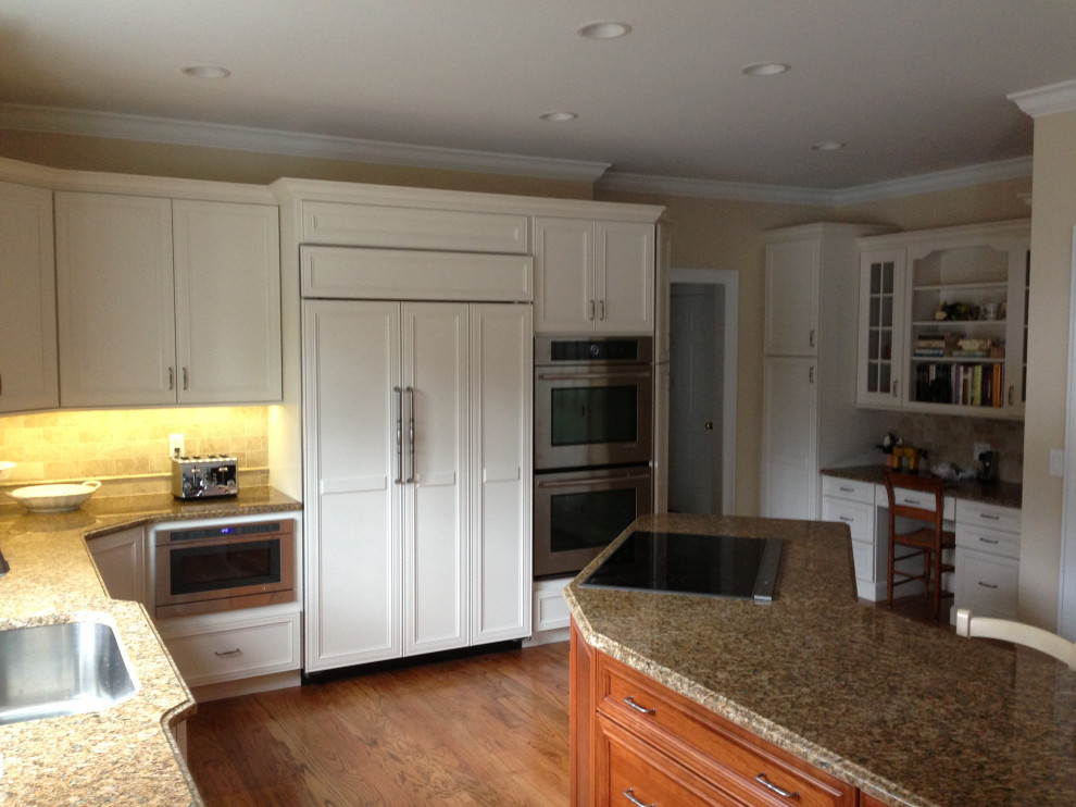 Large transitional u-shaped medium tone wood floor and brown floor eat-in kitchen photo in New York with an undermount sink, shaker cabinets, white cabinets, granite countertops, white backsplash, porcelain backsplash, stainless steel appliances, an island and multicolored countertops