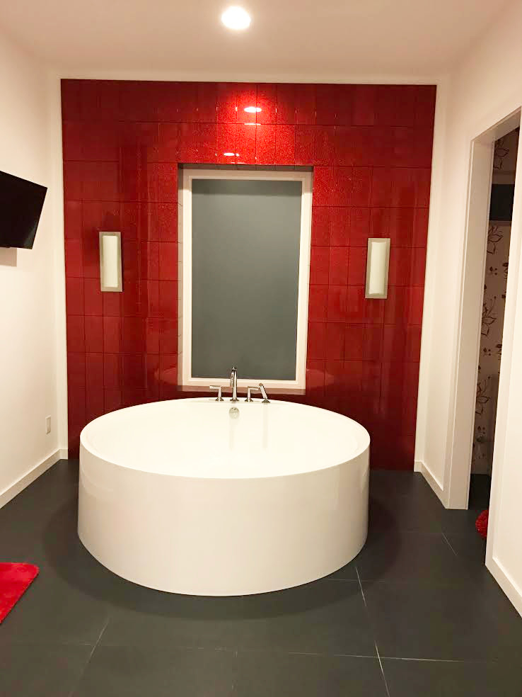 This is an example of a mid-sized modern master bathroom in New York with a hot tub, red tile, glass tile and white walls.