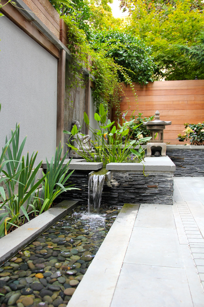 Photo of a small asian courtyard patio in DC Metro with a water feature, natural stone pavers and no cover.