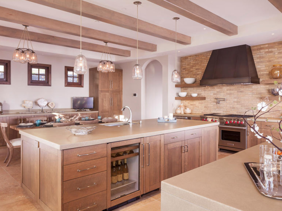 Photo of a mid-sized industrial l-shaped open plan kitchen in San Francisco with a farmhouse sink, shaker cabinets, dark wood cabinets, stainless steel benchtops, beige splashback, brick splashback, stainless steel appliances, light hardwood floors, with island and beige floor.