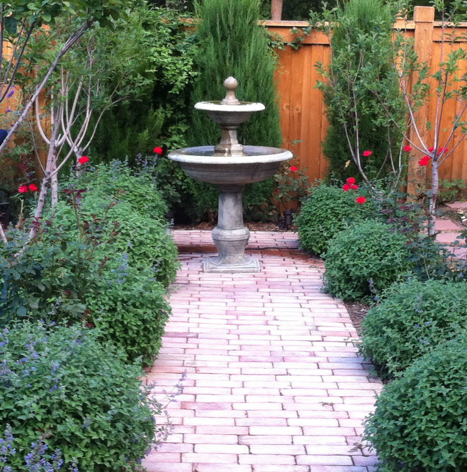 This is an example of a mid-sized transitional backyard full sun formal garden for summer in Denver with a water feature and brick pavers.