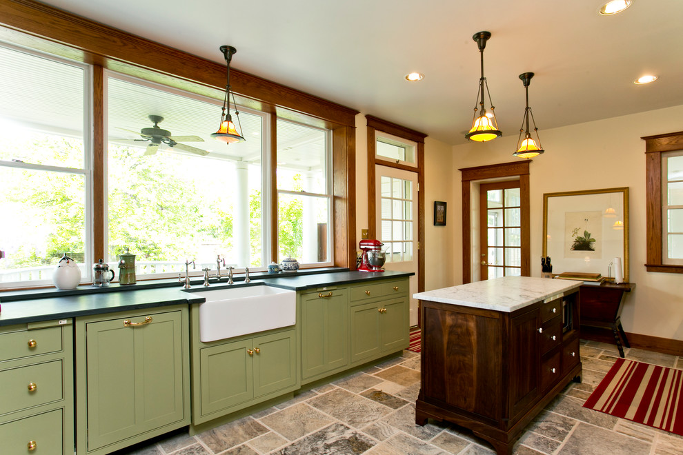 Mid-sized traditional u-shaped separate kitchen in DC Metro with a farmhouse sink, beaded inset cabinets, green cabinets, soapstone benchtops, beige splashback, ceramic splashback, stainless steel appliances, limestone floors, with island and brown floor.