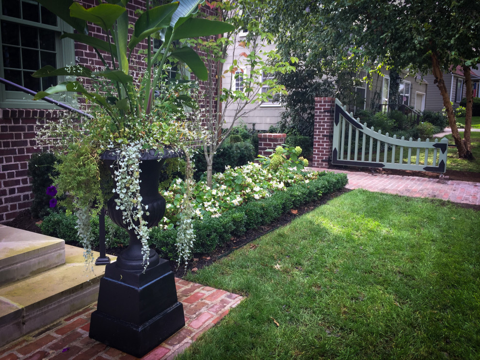 Photo of a mid-sized traditional front yard shaded formal garden for summer in Kansas City with with a gate, brick pavers and a wood fence.