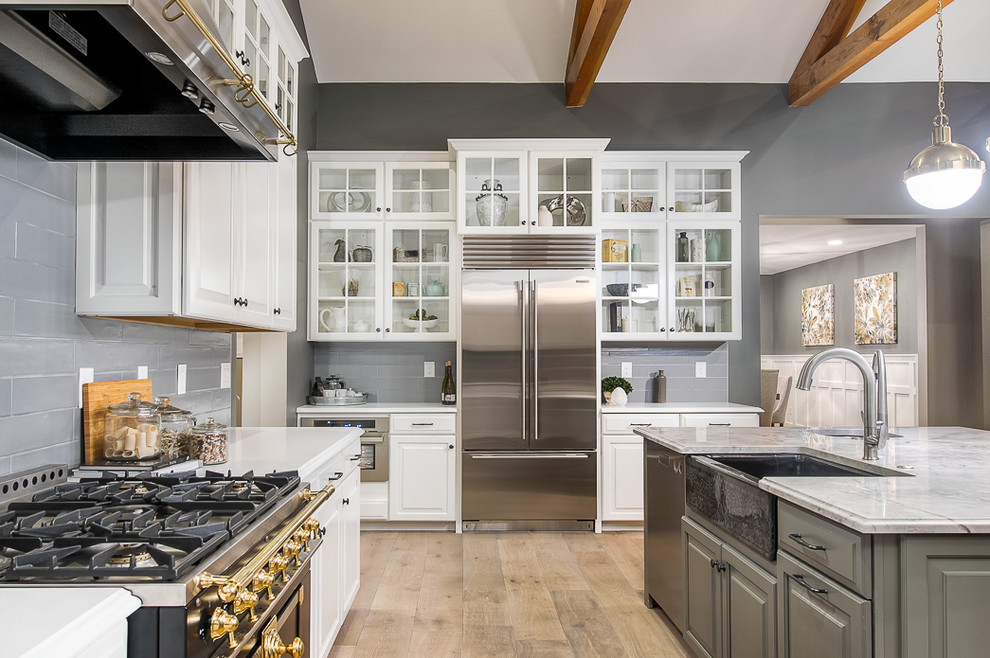 Inspiration for a large transitional light wood floor open concept kitchen remodel in Phoenix with a farmhouse sink, raised-panel cabinets, white cabinets, gray backsplash, glass tile backsplash, stainless steel appliances and an island
