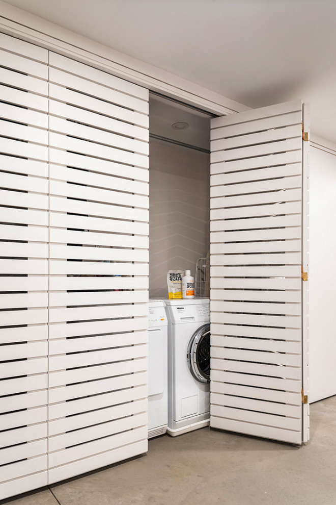 Inspiration for a small modern galley laundry cupboard in New York with white walls, a side-by-side washer and dryer and beige floor.