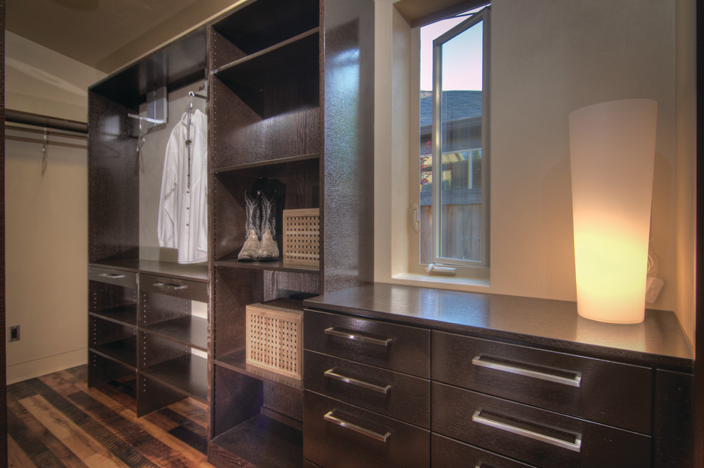 Small contemporary gender-neutral walk-in wardrobe in Other with flat-panel cabinets, dark wood cabinets, medium hardwood floors and brown floor.