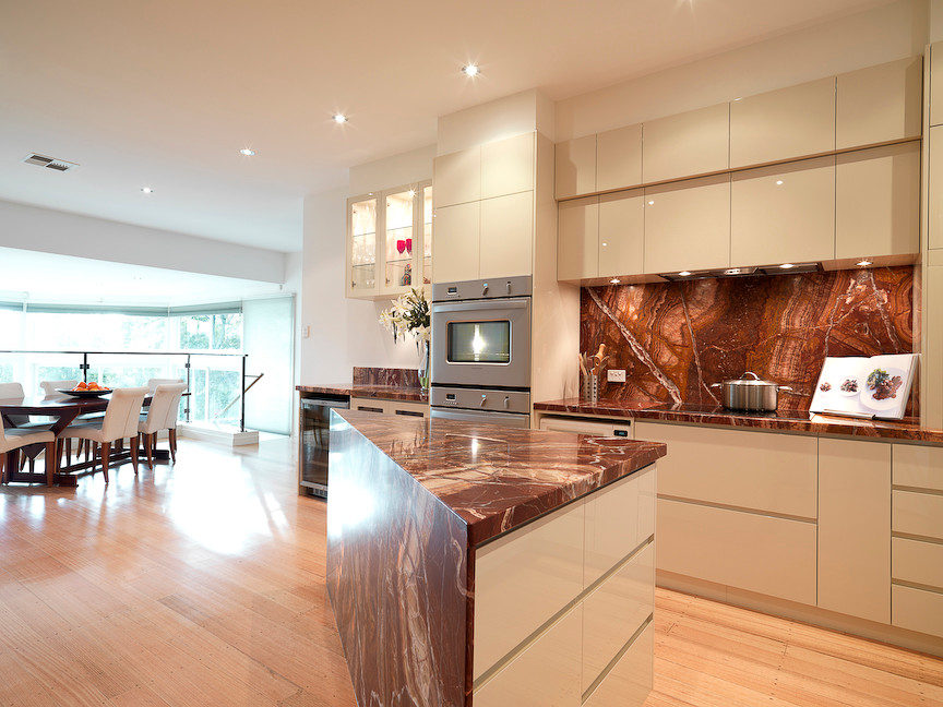 Inspiration for an expansive contemporary l-shaped eat-in kitchen in Melbourne with an undermount sink, flat-panel cabinets, white cabinets, multi-coloured splashback, stainless steel appliances, light hardwood floors and with island.